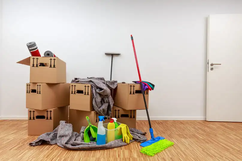 Moving boxes, cleaning supplies, and a mop in an empty room, for what is professional move out cleaning.