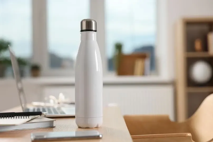 A white water bottle on a desk, a perfect visual aid for how to clean a water bottle.