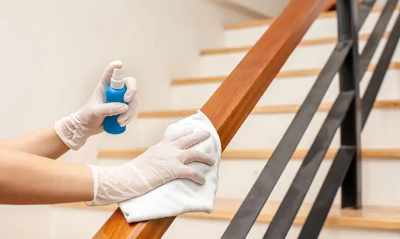 A person deep cleaning a handrail on a staircase, suggesting how long does it take for a deep cleaning.