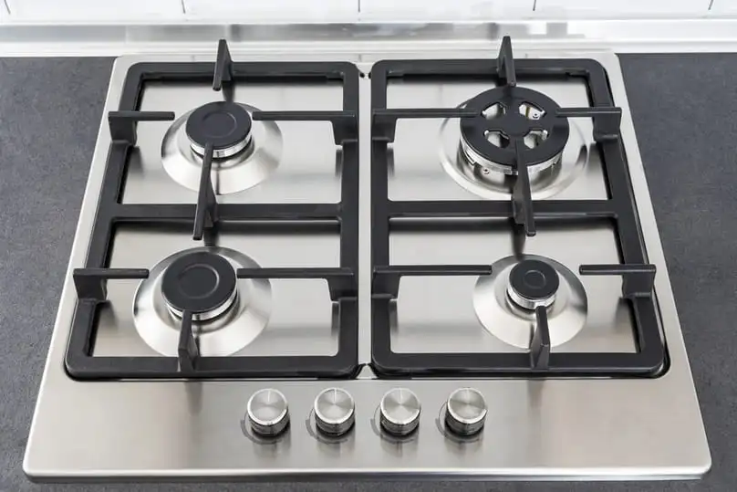 A clean stainless steel stovetop, emphasizes How to Clean Grease Off Kitchen Cabinets.
