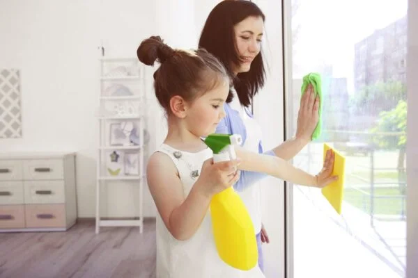 Mom and daughter cleaning window showing hacks working parents keep house clean.