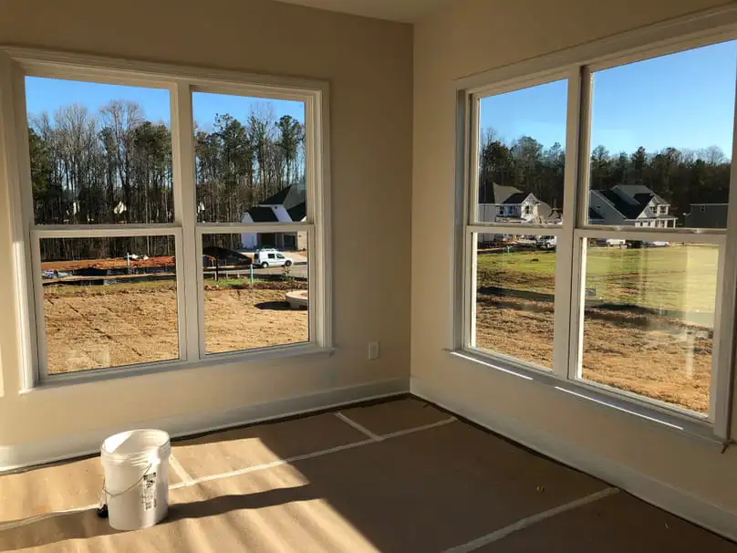 A newly constructed room with two large windows and a floor needing post construction cleaning rates